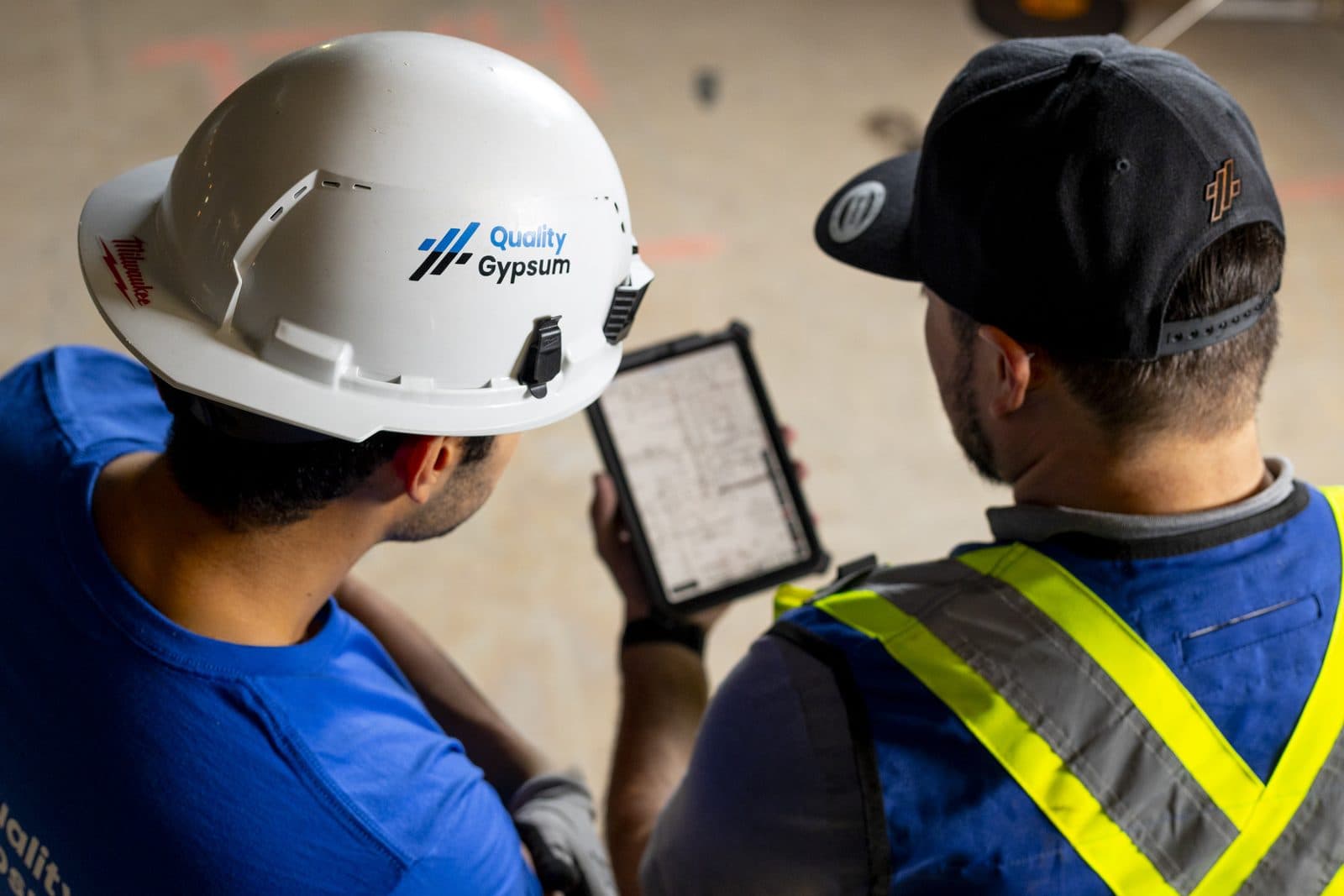 Quality Gypsum team reviewing project plans on a tablet on a Calgary jobsite